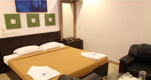 a room with a bed and a chair and a mirror at Hotel Metro in Kumbakonam