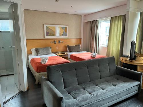 une chambre d'hôtel avec deux lits et un canapé dans l'établissement Flat Vila Olímpia ao lado do Shopping, à São Paulo