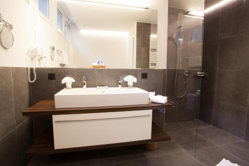 La salle de bains est pourvue d'un lavabo blanc et d'une douche. dans l'établissement Garni-Hotel Frohburg - Beau Rivage Collection, à Weggis