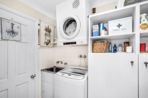 une petite cuisine blanche avec lave-linge et sèche-linge dans l'établissement Baileys Retreat, à Leura