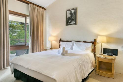 um quarto com uma grande cama branca e uma janela em Solitary View em Wentworth Falls