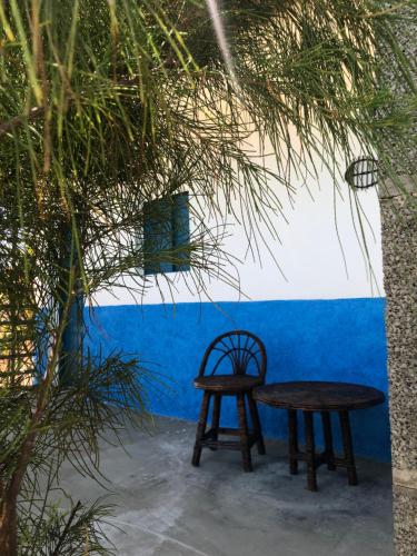 einem Holztisch und einem Stuhl vor einer blauen Wand in der Unterkunft Restaurante & Pousada Portal dos Ventos in Icapuí