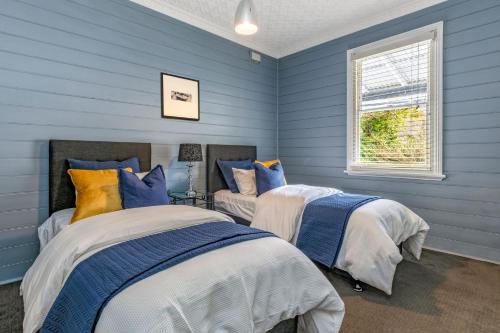 zwei Betten in einem Zimmer mit blauen Wänden in der Unterkunft Bluebell Cottage in Katoomba