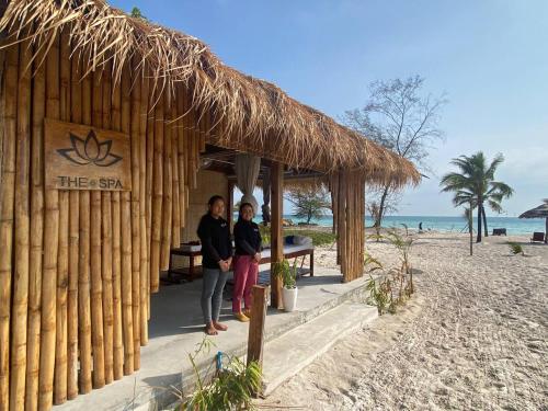 two people standing outside of a hut on the beach at You&Me Resort in Koh Rong Island