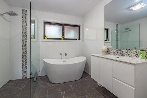 a white bathroom with a tub and a shower at Leura Pines in Leura