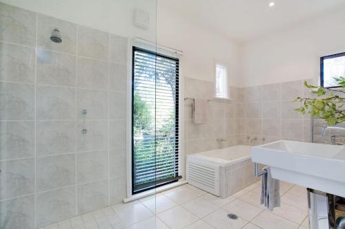 a bathroom with a sink and a toilet and a tub at White Cottage in Wentworth Falls