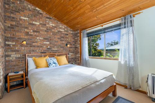 een bed in een kamer met een bakstenen muur bij Grey Gum Lodge in Woodford