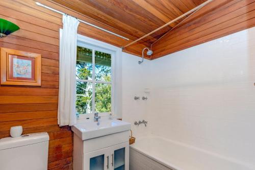 ein Badezimmer mit einer weißen Badewanne und einem Waschbecken in der Unterkunft Keira Cottage in Katoomba