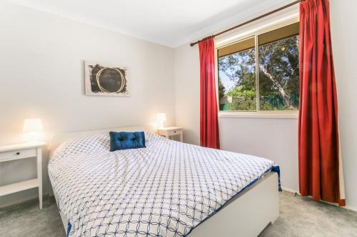 Schlafzimmer mit einem Bett und einem Fenster mit roten Vorhängen in der Unterkunft Minnehaha in Katoomba