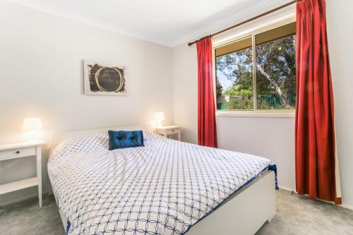 Un dormitorio con una cama y una ventana con cortinas rojas. en Minnehaha, en Katoomba
