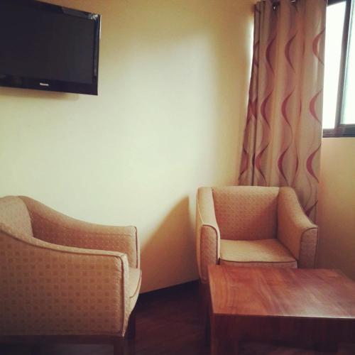 a room with two chairs and a tv on the wall at Nile Village Hotel & Spa in Jinja