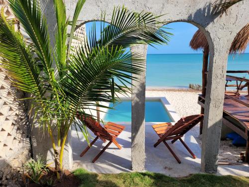 a couple of chairs and a palm tree on the beach at Puerto del Cielo in Chuburná