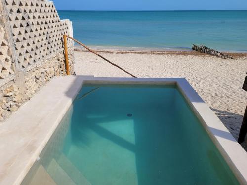 a swimming pool next to a beach with the ocean at Puerto del Cielo in Chuburná