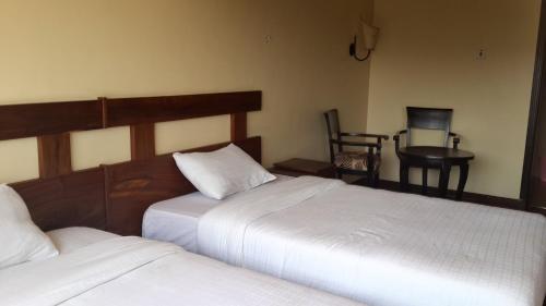 a bedroom with two beds and a table and a chair at Nile Village Hotel & Spa in Jinja