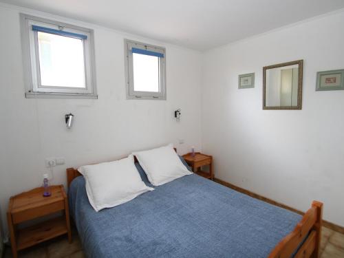 um quarto com uma cama azul e 2 janelas em Appartement Argelès-sur-Mer, 2 pièces, 4 personnes - FR-1-309-255 em Argelès-sur-Mer