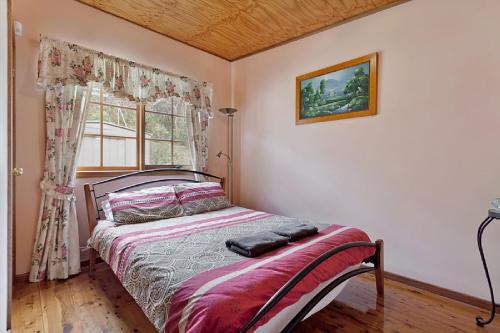 een bed in een kamer met een raam en een bed sidx sidx sidx bij Observatory Cottage in Leura