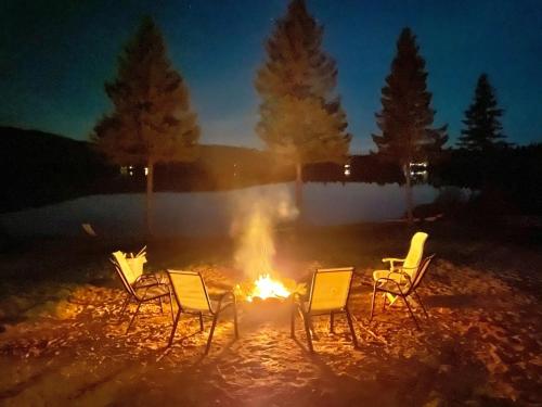 a group of chairs around a fire at night at La Couronne boréale in Rivière-Rouge