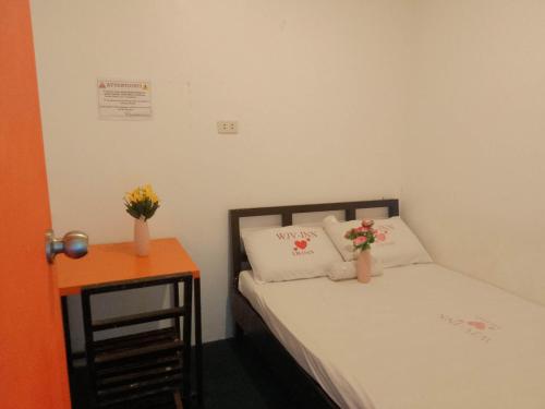 una piccola camera con un letto e un tavolo con fiori di WJV INN LILOAN a Liloan