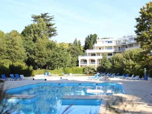 une piscine avec des chaises et un bâtiment en arrière-plan dans l'établissement Appartement 2 pièces avec terrasse, parking, piscines - à 300m de la plage à La Baule - FR-1-245-18, à La Baule