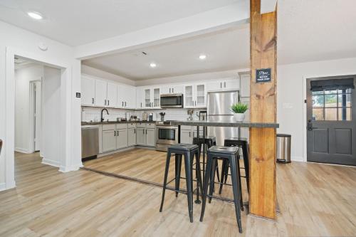 a kitchen with white cabinets and bar stools at The Gated Modern Home Near NRG and Medical Center in Houston