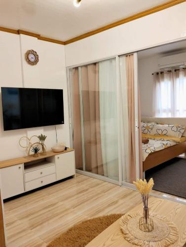 een woonkamer met een flatscreen-tv en een bed bij Catalena Transient House Bayugan City in Bayugan City