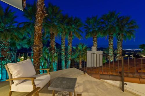 a balcony with a couch and palm trees at night at Big Horn Desert Estate Luxury Smarthome - Amazing Pool & Game Room! in Palm Desert