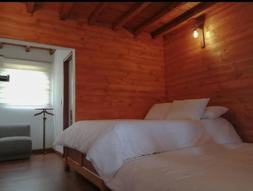 una camera con un letto bianco su una parete in legno di Villa Rosario a Aquitania