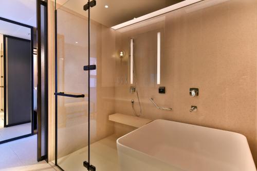 八里區的住宿－八里福朋喜來登酒店，带淋浴和白色浴缸的浴室