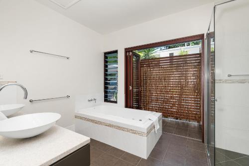 a bathroom with a tub and a sink and a shower at Onda Beach Clifton Beach in Clifton Beach