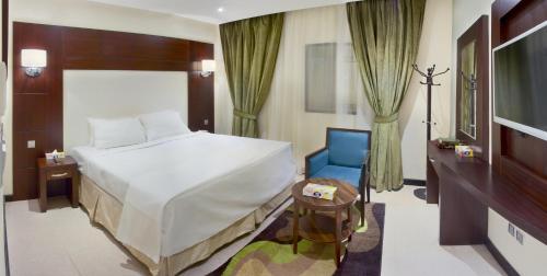 メッカにあるMina Concorde Hotelのベッドルーム(大型ベッド1台、青い椅子付)