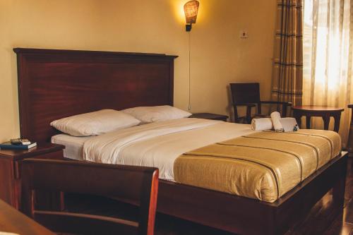 a bedroom with a large bed with a wooden headboard at Nile Village Hotel & Spa in Jinja