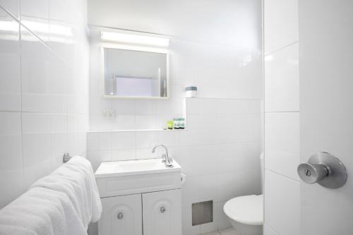 a white bathroom with a sink and a toilet at Meadow Inn Hotel-Motel in Melbourne