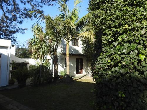 une maison blanche avec des palmiers dans la cour dans l'établissement Verano, à Punta del Este