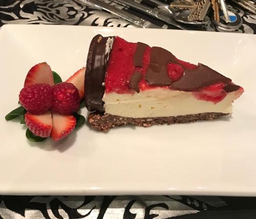 a piece of cake on a white plate with strawberries at Hilltop Motel in Broken Hill