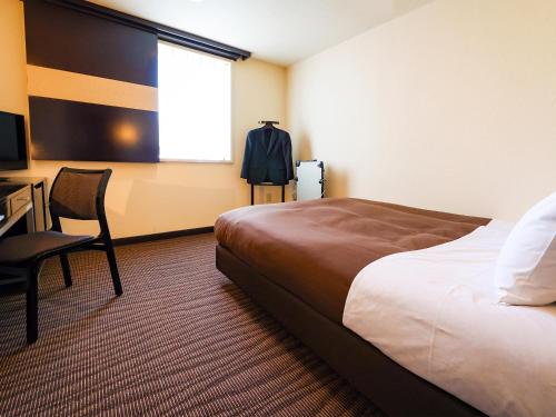 a hotel room with a bed and a desk and a window at Fukui Hotel in Obihiro