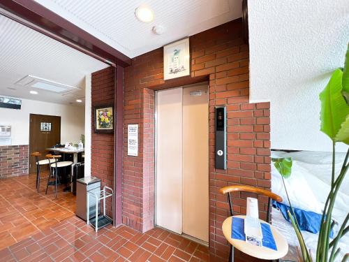 Habitación con pared de ladrillo, puerta y mesa. en ビジネスホテル ごとう＠ＮＥＴ, en Kure
