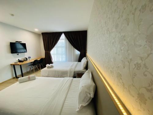 um quarto de hotel com duas camas e uma secretária em Hotel U and Me em Kulai