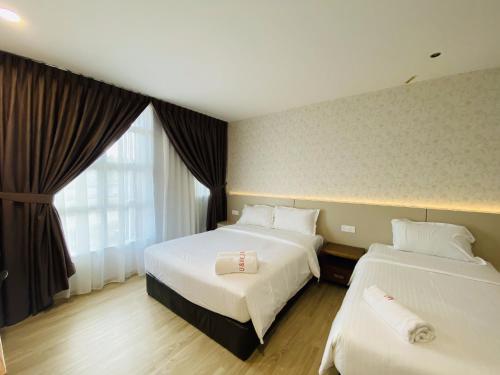 um quarto de hotel com duas camas e uma janela em Hotel U and Me em Kulai