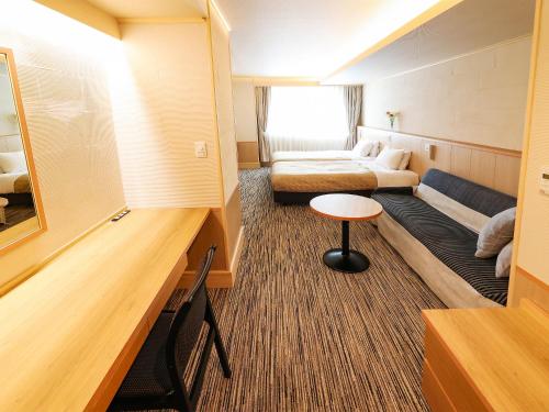 a small room with two beds and a table at Fukui Hotel in Obihiro