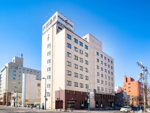 a tall white building on the corner of a street at Fukui Hotel in Obihiro