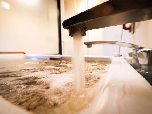 a kitchen sink with water coming out of a faucet at Fukui Hotel in Obihiro