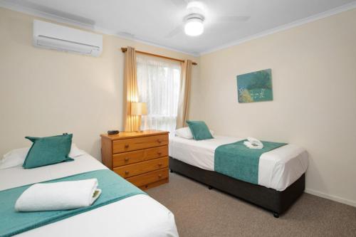 1 dormitorio con 2 camas, vestidor y ventana en The Shores Holiday Apartments, en Mackay