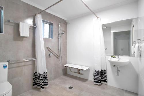 a bathroom with a shower and a sink and a toilet at The Shores Holiday Apartments in Mackay