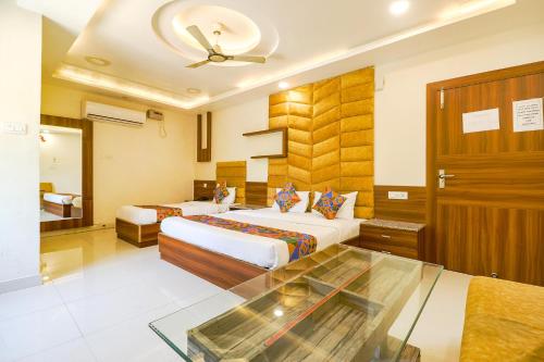 a hotel room with two beds and a glass table at FabHotel Royal Aanandam in Gwalior