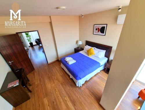 a bedroom with a blue bed and wooden floors at Margarita Apartamentos in Cochabamba