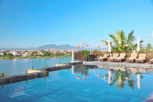 uma piscina com espreguiçadeiras na água em Little Riverside Hoi An . A Luxury Hotel & Spa em Hoi An