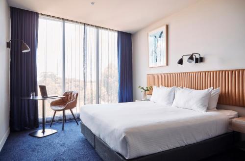 Epping的住宿－Mantra Melbourne Epping，配有一张床、一张书桌和一扇窗户的酒店客房