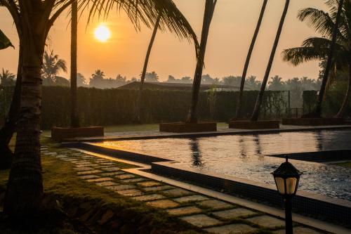 a swimming pool with palm trees and a street light at Sawantwadi Palace Boutique Art Hotel in Sawantwadi