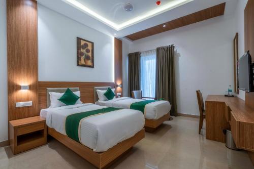 a hotel room with two beds and a television at Hotel Panoramic in Ernakulam