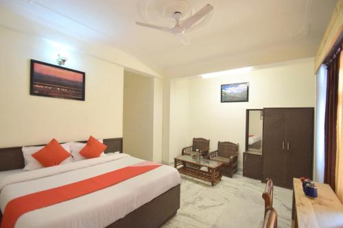 Habitación de hotel con cama y TV en Hotel Sunshine Dharamshala, en Dharamshala